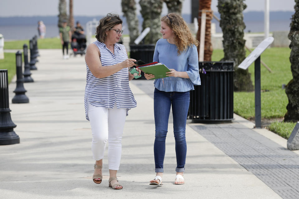 In this Friday, April 10, 2020, photo Ebru Ural, left, and her daughter Serra Sowers take a walk while discussing colleges to choose without actually visiting them at a park in Sanford, Fla. The coronavirus pandemic has changed the process of college visits to virtual interviews and visits. (AP Photo/John Raoux)