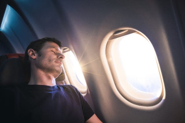 Man sleeping on airplane during sunrise