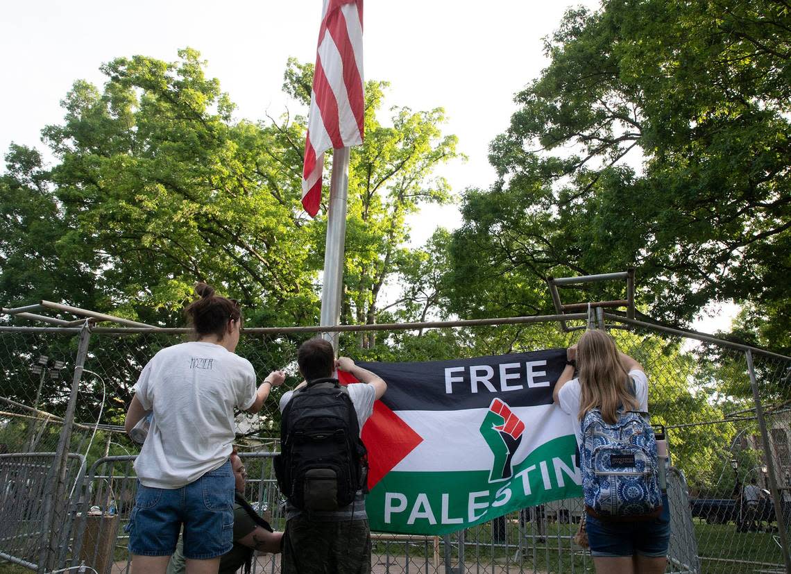 People attach a “Free Palestine” flag to a fence barrier surrounding the flagpole on the campus of UNC-Chapel Hill on Tuesday, April 30, 2024. UNC-Chapel Hill police charged 36 members of a pro-Palestinian “Gaza solidarity encampment” Tuesday morning after warning the group to remove its tents from campus or face possible arrest, suspension or expulsion from the university.