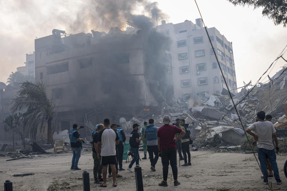 En esta imagen de archivo, reporteros observan mientras palestinos inspeccionan un edificio alcanzado por un bombardeo israelí en la Ciudad de Gaza, 8 de octubre de 2023. El limitado número de periodistas que están en Gaza tratan de informar sobre la guerra con Israel mientras sufren los mismos problemas que la asediada población palestina de la Franja. (AP Foto/Fatima Shbair, archivo).