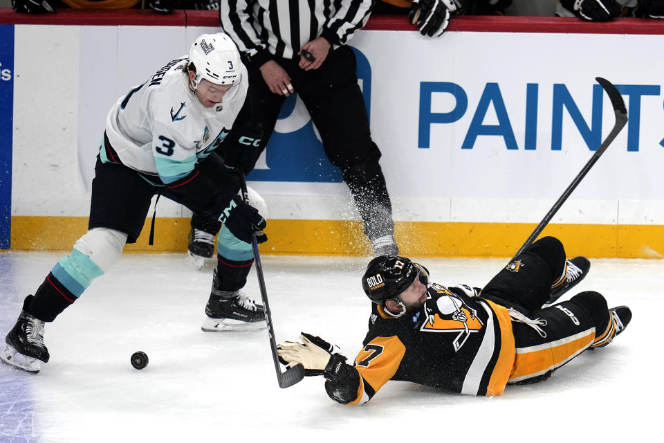 Pittsburgh Penguins' Bryan Rust (17) is checked off the puck by Seattle Kraken's Will Borgen during the first period of an NHL hockey game in Pittsburgh, Monday, Jan. 15, 2024. (AP Photo/Gene J. Puskar)