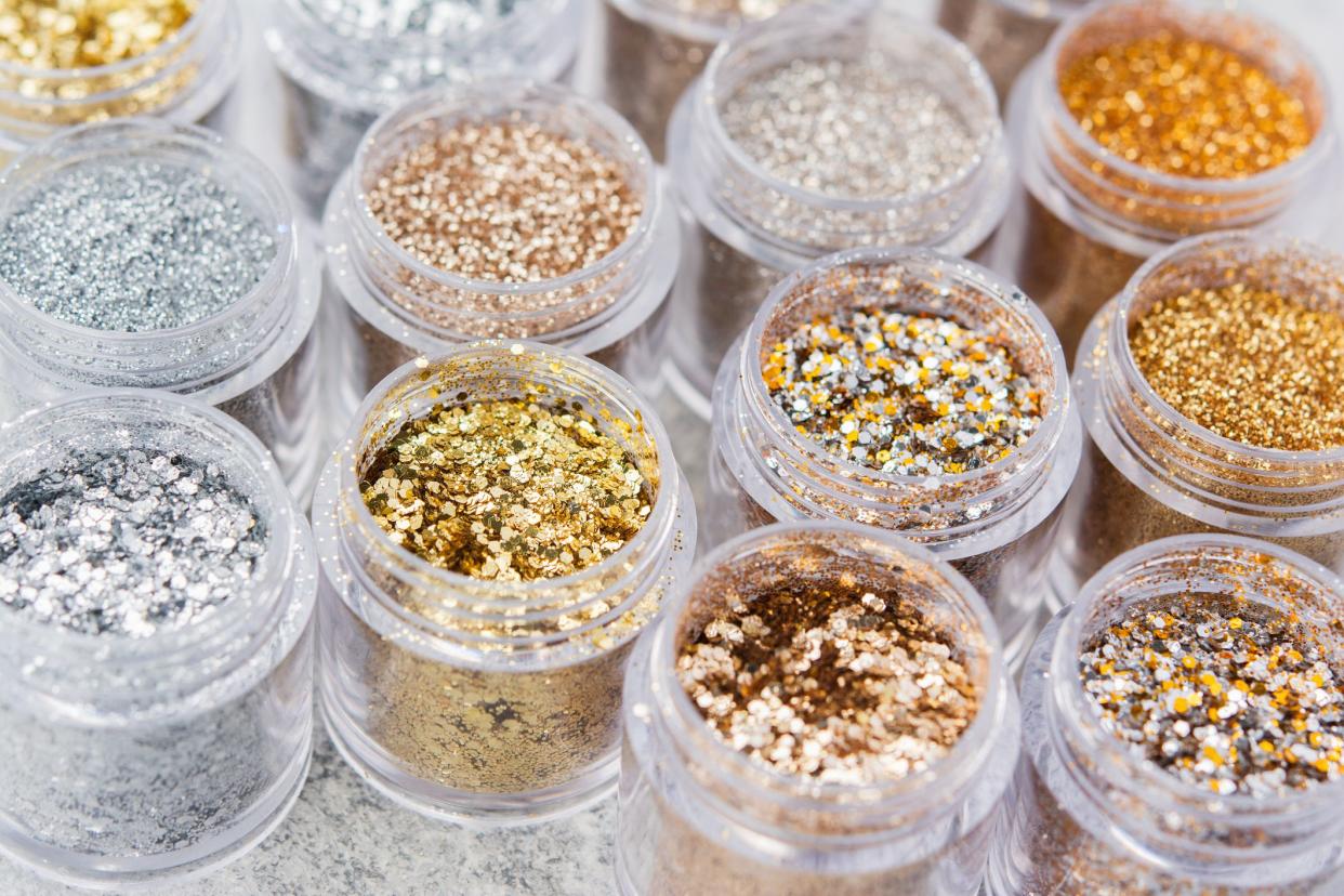 Beautiful glitter in golden and silver shades in small glass jars, selective focus