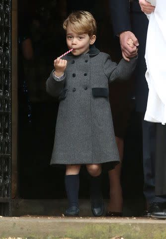 <p>Danny Martindale/WireImage</p> Prince George tries a candy cane as he leaves church in Bucklebury on Christmas in 2016.