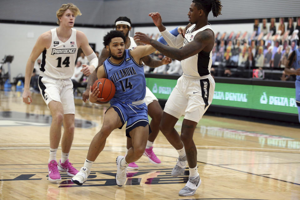 Villanova's Caleb Daniels (14) drives to the basket as Providence's Greg Gantt (1) and Noah Horchler (14) defend during an NCAA college basketball game in Providence, R.I., Saturday, March 6, 2021. (AP Photo/Stew Milne)