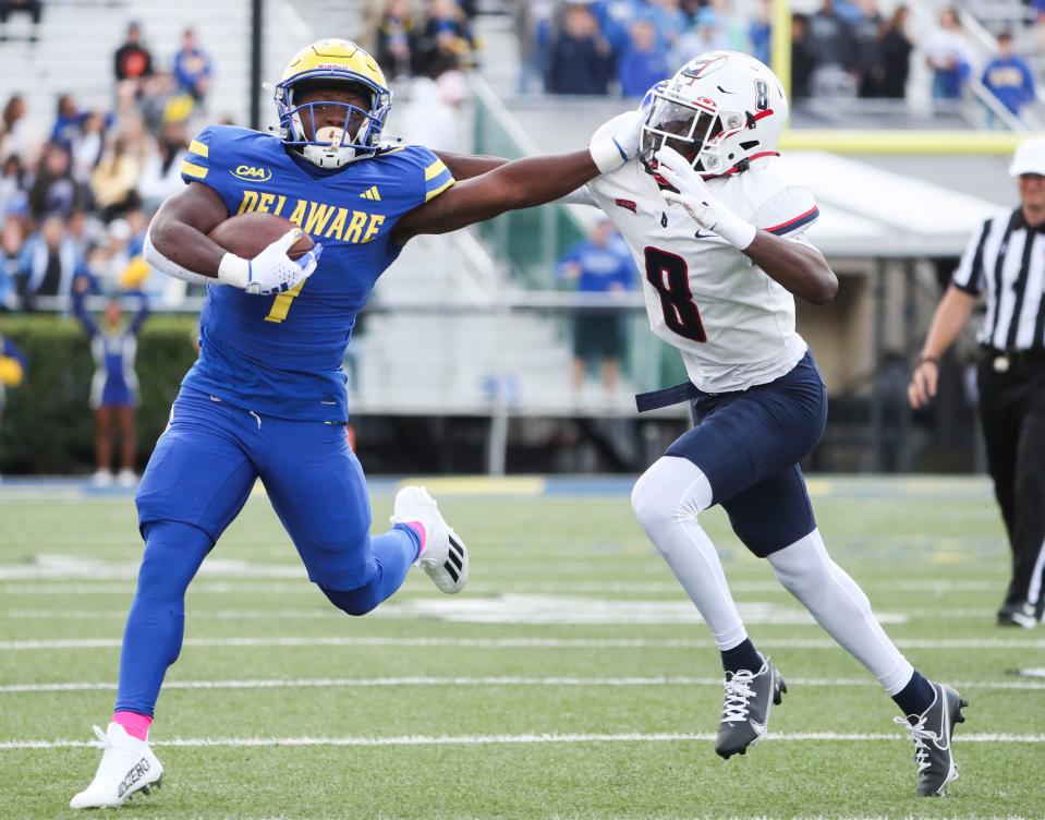 Delaware running back Kyron Cumby stiff arms Duquesne defensive back Ayden Garnes in the first quarter of the Blue Hens' 43-17 win at Delaware Stadium, Saturday, Oct. 7, 2023.
