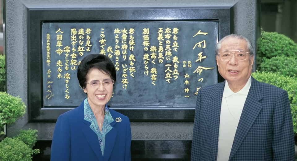 Daisaku Ikeda and his wife Kamineko Ikeda (left) pose for a photo in front of the commemorative plaque of the work. As the leader of the society, Daisaku Ikeda has written the novels 