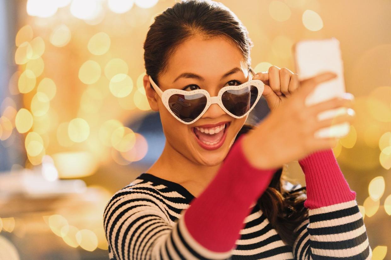 woman wearing heart shaped glasses taking selfie