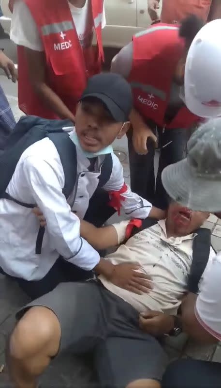 A man attacked in the street by pro-military supporters is helped by people in Yangon