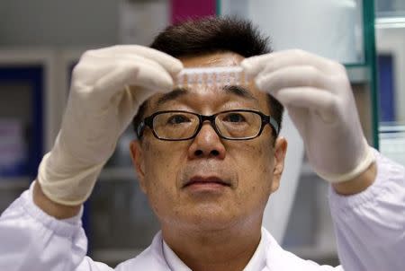 Group Leader, Dr Masafumi Inoue of Agency for Science Technology and Research's (A*STAR) Experimental Therapeutics Centre holds up a sample to be tested with the Zika virus diagnostic test kit at their laboratory in Singapore, February 10, 2016. REUTERS/Edgar Su