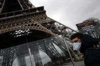 A man wearing a mask walks pasts the Eiffel tower closed after the French government banned all gatherings of over 100 people to limit the spread of the virus COVID-19, in Paris, Saturday, March 14, 2020. For most people, the new coronavirus causes only mild or moderate symptoms. For some it can cause more severe illness, especially in older adults and people with existing health problems. (AP Photo/Christophe Ena)