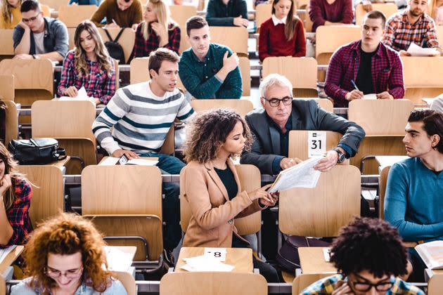 Mature professor assisting his female student with a lecture in a textbook at lecture hall. (Photo: skynesher via Getty Images)