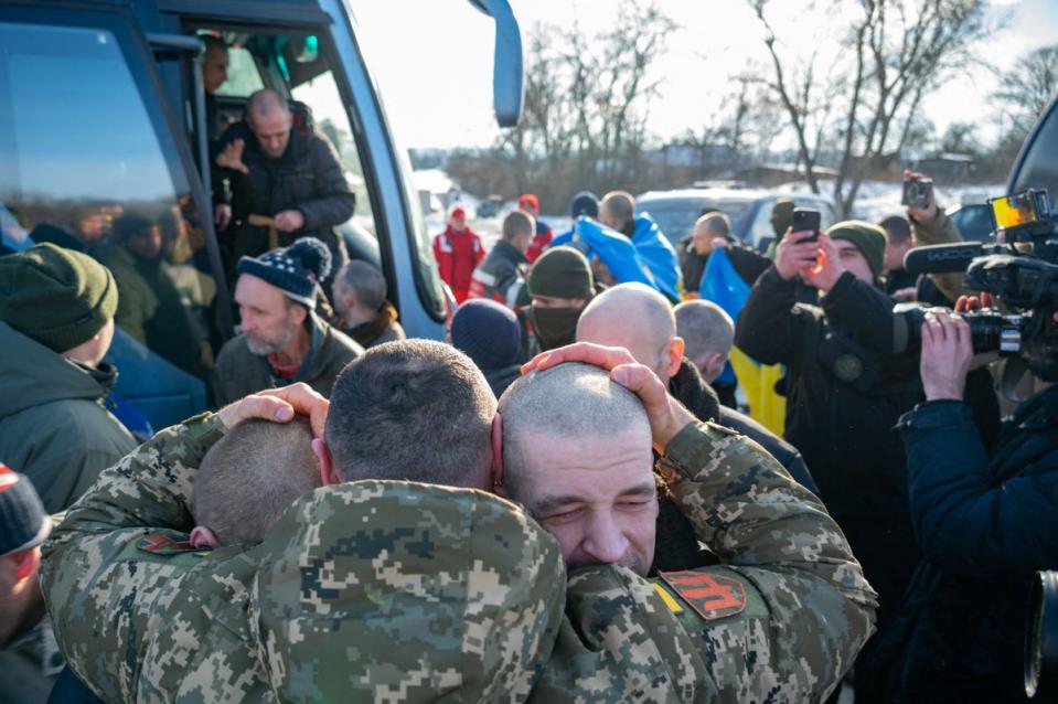 A Ukrainian serviceman embraces prisoners of war (POWs) after a swap, amid Russia’s attack on Ukraine, at an unknown location in Ukraine (via REUTERS)