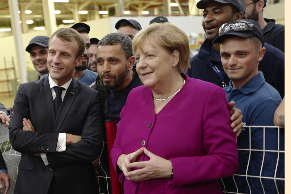 French President Emmanuel Macron, left, and German Chancellor Angela Merkel pose as they talk to Airbus French and German employees after visiting the assembly line of the Airbus A350 in Toulouse, southwestern France, Wednesday, Oct.16, 2019. French President Emmanuel Macron and German Chancellor Angela Merkel are meeting in southern France, one day before a key EU summit that may approve a divorce deal with Britain. (AP Photo/Frederic Scheiber, Pool)