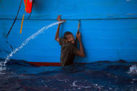 <p>A man holds himself on the side of a boat after jumping into the sea from a crowded wooden boat during a rescue operation at the Mediterranean sea, about 13 miles north of Sabratha, Libya, Monday, Aug. 29, 2016. (Photo: Emilio Morenatti/AP) </p>