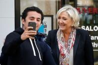 Marine Le Pen (R), French National Front (FN) political party leader and candidate for French 2017 presidential election, poses for a selfie as she leaves the haidresser in front of her campaign headquarters in Paris, France, April 24, 2017 the day after the first round of presidential elections where Le Pen ended in second place behind En Marche ! movement candidate. REUTERS/Charles Platiau