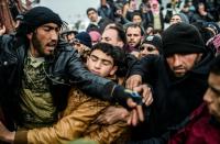 Syrian refugees jostle each other near the Turkish border crossing on February 6, 2016