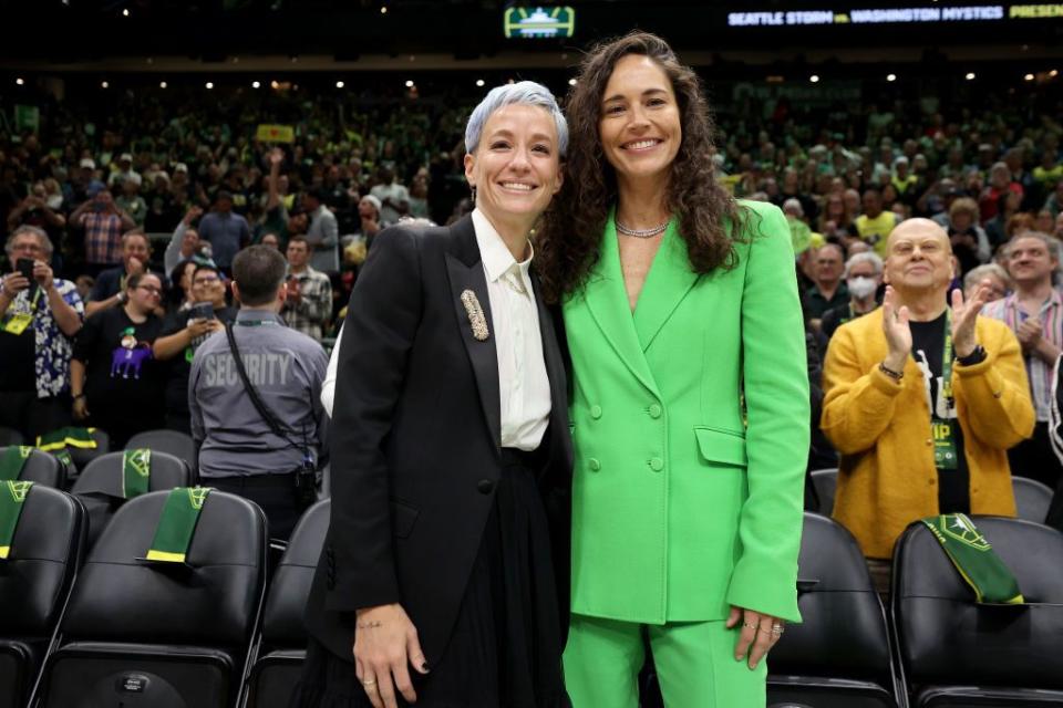 megan rapinoe and sue bird smiling for a photo while courtside at a basketball game