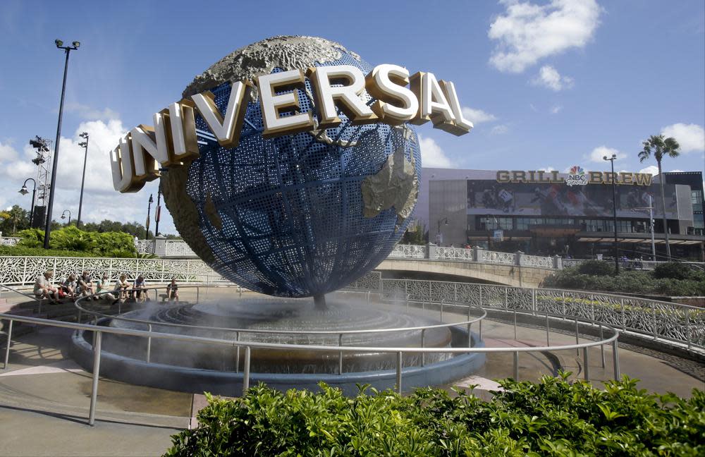 In this Thursday, Oct. 22, 2015 file photo, park guests relax and cool off with a water mist under the globe at Universal Studios City Walk in Orlando, Fla. (AP Photo/John Raoux)