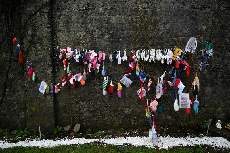 Calcetines para niños y otros artículos cuelgan de una pared en el cementerio de Tuam, donde los cuerpos de 796 bebés fueron descubiertos en el sitio de un antiguo hogar católico para madres solteras y sus hijos el día en que una investigación ordenada por el gobierno sobre antiguos hogares administrados por la Iglesia. para madres solteras se publica formalmente en Tuam, Irlanda