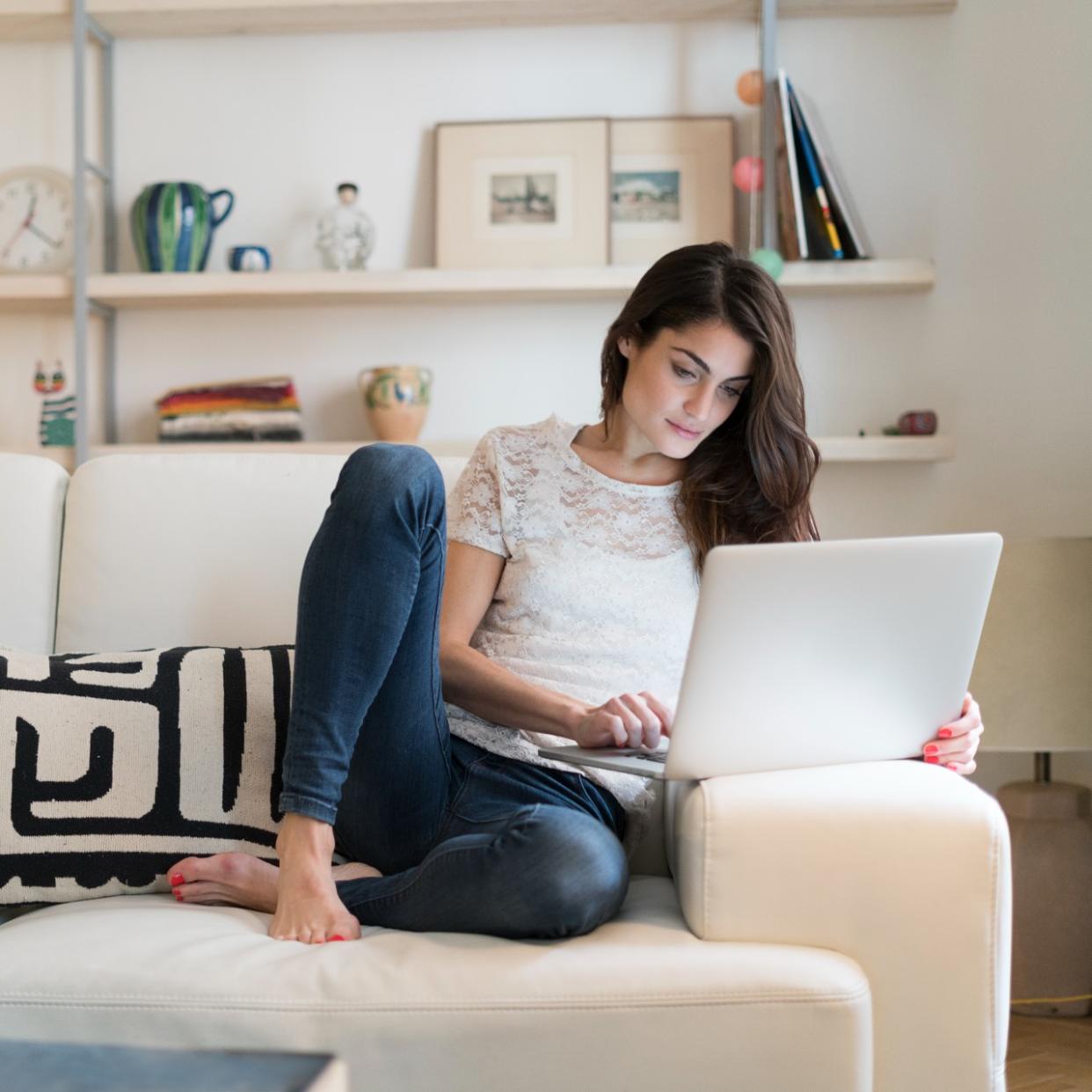  Woman on laptop on couch shopping for virtual gift  