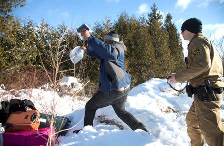 The man runs for the border after taking his family's passports from a U.S. border patrol officer as he was detained after his family crossed the U.S.-Canada border into Hemmingford, Canada, from Champlain in New York. REUTERS/Christinne Muschi