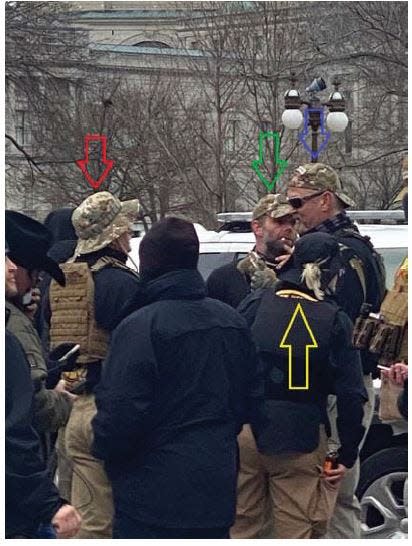 An open source photo obtained by the FBI identifies alleged Oath Keepers and co-conspirators in the Jan. 6 Capitol Riot. They are: Kelly Meggs (blue arrow), Graydon Young (red arrow), Laura Steele (yellow arrow) and Kenneth Harrelson (green arrow). (FBI/DOJ)
