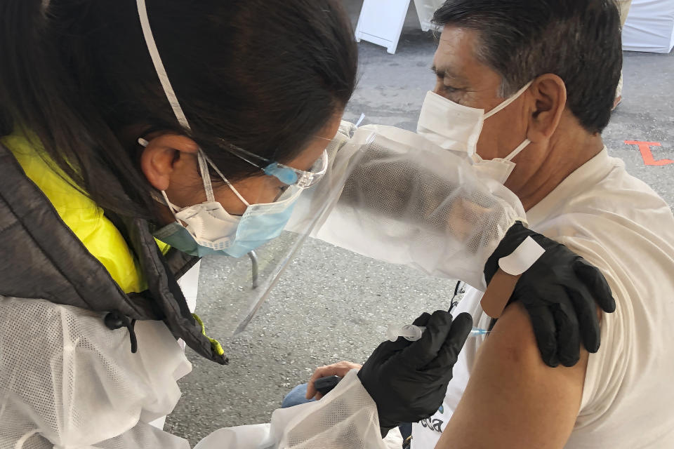 Juan Delgado, 73, right, receives a COVID-19 vaccine shot from a health care worker at a vaccination site in the Mission district of San Francisco, Monday, Feb. 8, 2021. Counties in California and other places in the U.S. are trying to ensure they vaccinate people in largely Black, Latino and working-class communities that have borne the brunt of the coronavirus pandemic. San Francisco is reserving some vaccines for seniors in the two ZIP codes hit hardest by the pandemic. (AP Photo/Haven Daley)