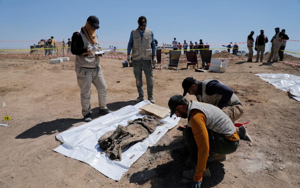 Ministry of Health staff collect remains from the mass grave - REUTERS/Abdullah Rashid