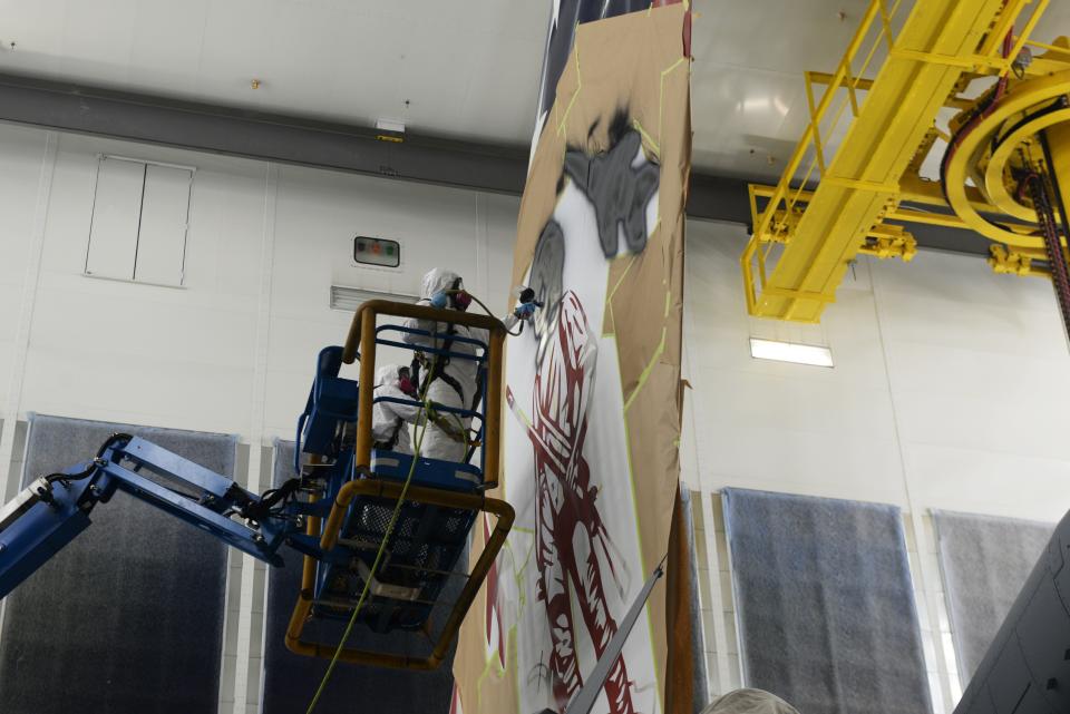 Staff Sgt. Cory Lewis, a 157th Air Refueling Wing structural maintenance Airman, paints a 16-foot-tall Minute Man on the tail of the Spirit of Portsmouth, a KC-46A assigned to the wing, while fellow maintainer Tech. Sgt. Jay Cunha looks on at Joint Base Elmendorf-Richardson in Alaska.