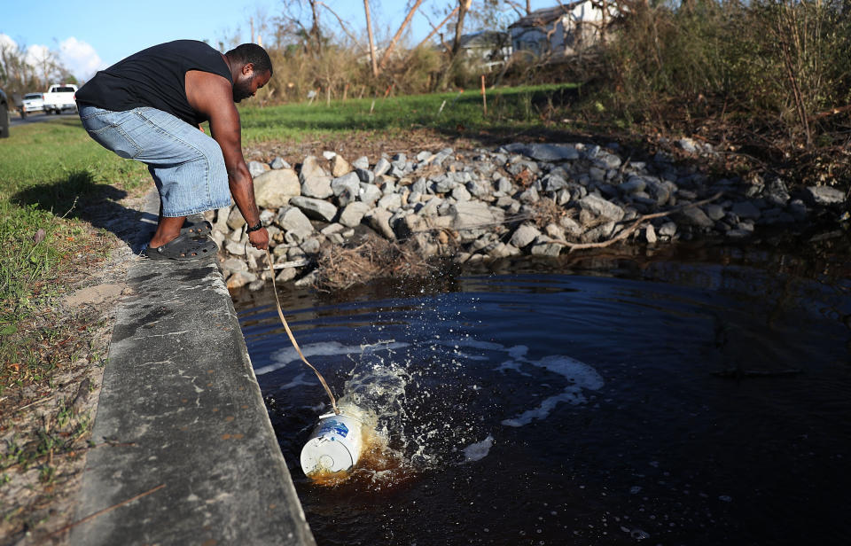 Kenston Robinson uses a bucket to get water from a canal to flush his family's toilet after much of the municipal infrastructure was damaged in Panama City.