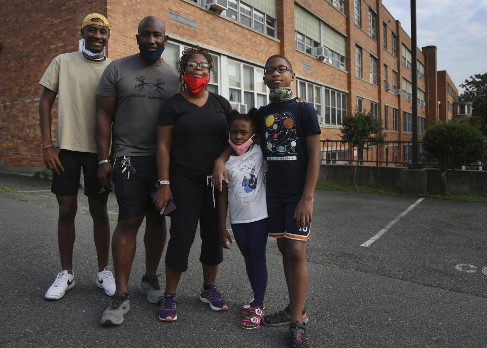 The Burgess family, from left, Jonathan Jr., 15, Jonathan Sr., Shante, Ava, 6, and Evan, 10, stand outside St. Francis Xavier in Newark, New Jersey, on Thursday, Aug. 6, 2020, as they meet with other parents to discuss the school's closure. "Closing an inner-city school during a pandemic is not the most godly thing to do," Shante Burgess said. (AP Photo/Jessie Wardarski)