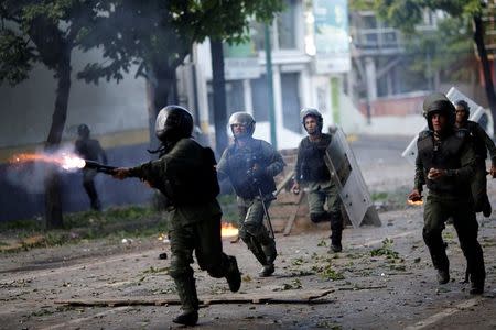 A riot security force member fires his weapon at a rally during a strike called to protest against Venezuelan President Nicolas Maduro's government in Caracas. REUTERS/Ueslei Marcelino