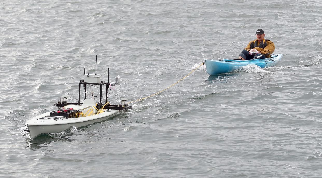Troy Barnhart, program manager with Serco, is towed in a kayak behind the ARCHER Environmental unmanned surface vehicle as it heads for the Port of Illahee Pier on Wednesday, Oct. 25, 2023.