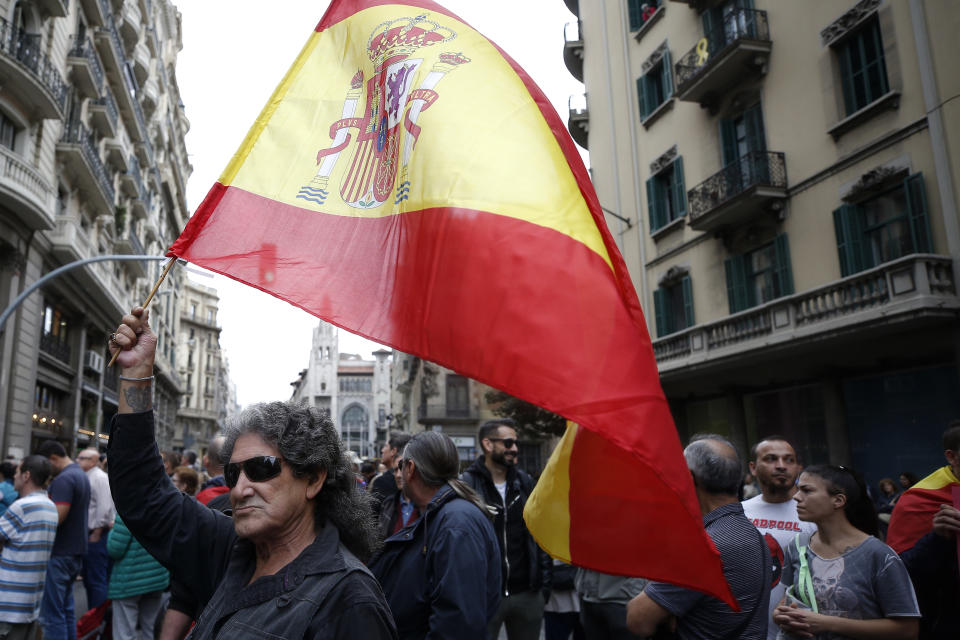 A man holds a Spanish flag near to a police station in Barcelona, Spain, Monday, Oct. 21, 2019. Barcelona and the rest of the restive Spanish region of Catalonia are reeling from several days of violent protests for the sentencing of 12 separatist leaders to lengthy prison sentences, with riots breaking out at nightfall following huge peaceful protests each day since Monday's Supreme Court verdict. (AP Photo/Manu Fernandez)