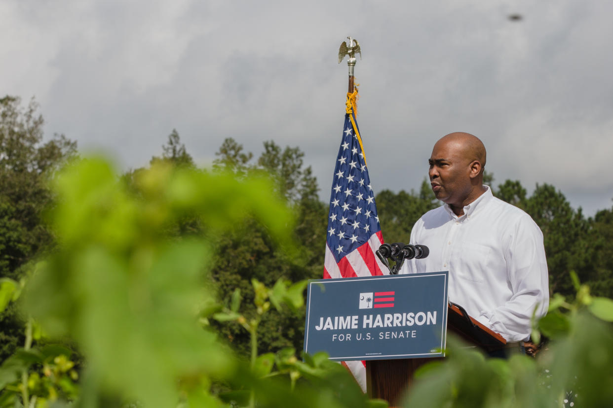 Jaime Harrison speaks at a podium at an outdoor event