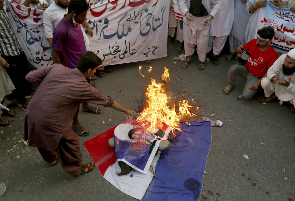 Supporters of a religious group burn defaced images of French President Emmanuel Macron with a representation of a French flag during a protest against the French president and republishing of caricatures of the Prophet Muhammad they deem blasphemous, in Karachi, Pakistan, Saturday, Oct. 31, 2020. Muslims have been calling for both protests and a boycott of French goods in response to France's stance on caricatures of Islam's most revered prophet. (AP Photo/Fareed Khan)