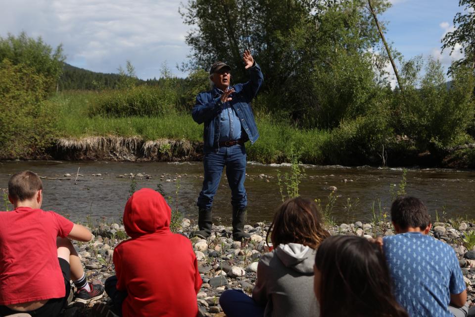 Eric Mitchell, a syilx knowledge keeper, shares a captikʷł story with Youth from Okanagan Indian Band’s Cultural Immersion School prior to a salmon ceremonial release hosted by the Okanagan Nation Alliance at the Salmon River in syilx Okanagan territory on June 19, 2024. Photo by Aaron Hemens