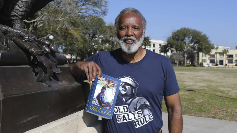 Reuben Green, a retired Black Naval officer, poses with the book he authored, "Black Officer, White Navy," at Memorial Park in Jacksonville, Fla., Friday, Feb. 26, 2021. (AP Photo/Gary McCullough)