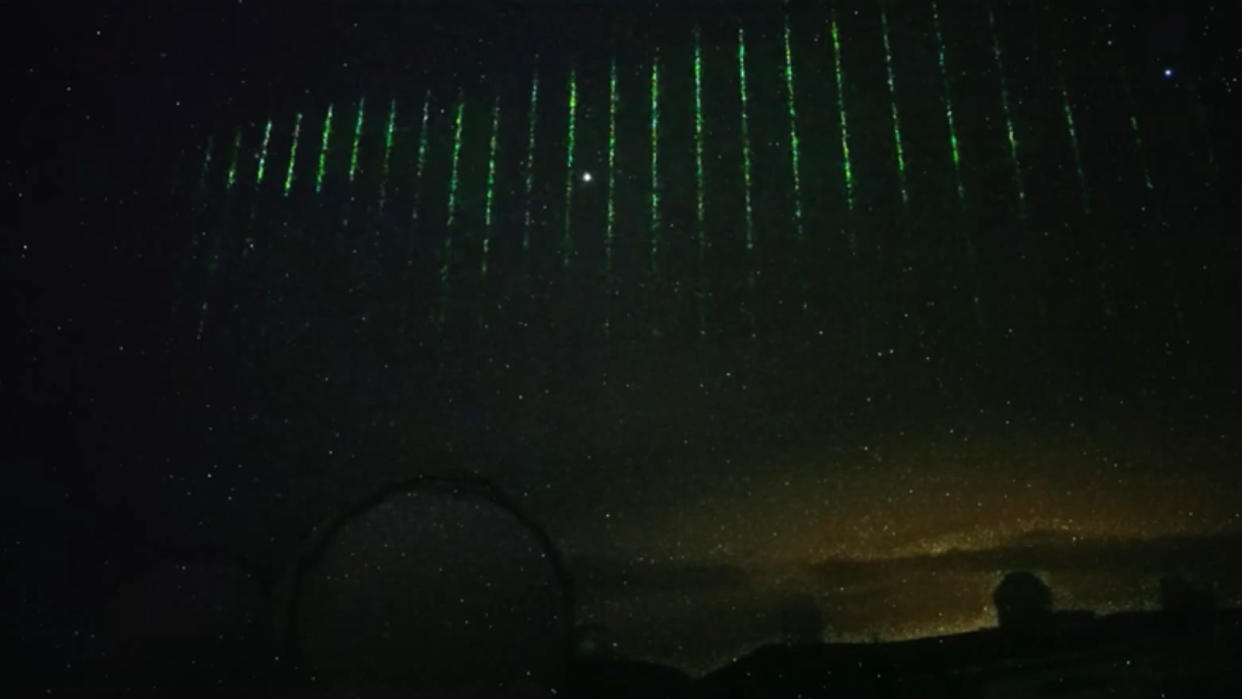  A time-lapse image of the green laser pulses flashing across the night sky. 