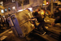 Protestors push a garbage container on to the street during clashes between protestors and police in Barcelona, Spain, Wednesday, Oct. 16, 2019. Spain's government said Wednesday it would do whatever it takes to stamp out violence in Catalonia, where clashes between regional independence supporters and police have injured more than 200 people in two days. (AP Photo/Bernat Armangue)