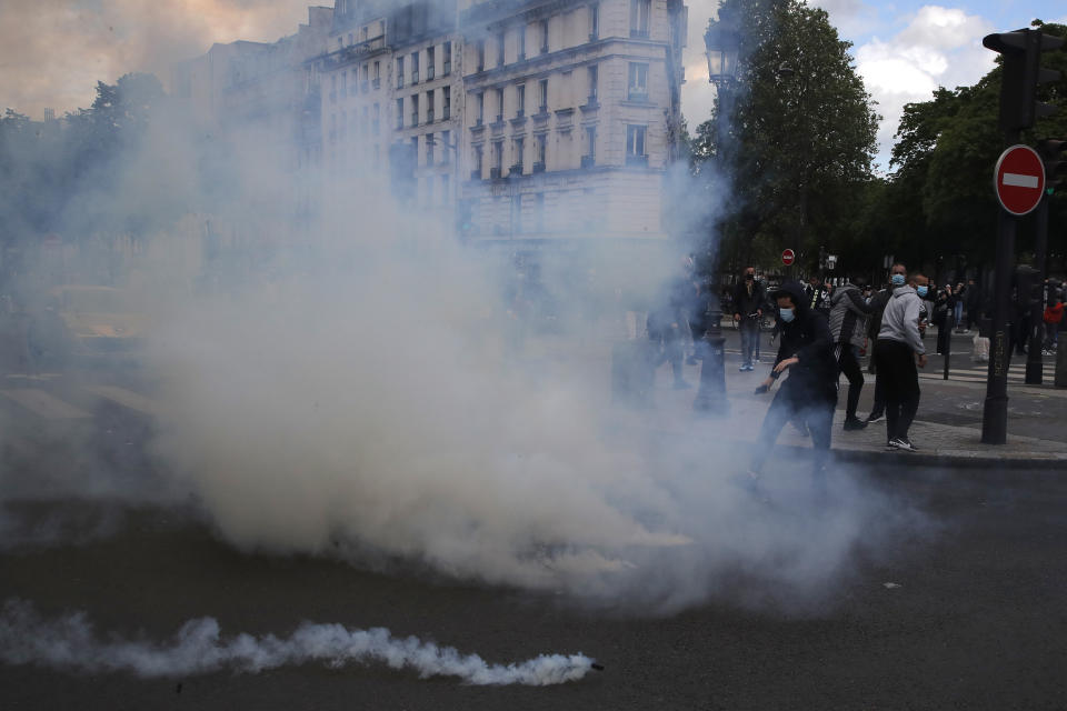 Demonstrators kick in tear gas grenades fired by police forces during a banned protest in support of Palestinians in the Gaza Strip, Saturday, May, 15, 2021 in Paris. Marches in support of Palestinians in the Gaza Strip were being held Saturday in a dozen French cities, but the focus was on Paris, where riot police got ready as organizers said they would defy a ban on the protest. (AP Photo/Michel Euler)