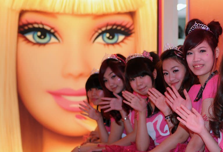 Waitresses wave in front of a Barbie poster during the opening ceremony of a Barbie-themed restaurant in Taipei on January 30, 2013. US toymaker Mattel has licensed Taiwan's restaurant group Sinlaku to operate the Barbie Cafe and hopes that the new establishment in a bustling shopping district in the capital Taipei will help promote Barbie as a fashion brand