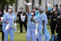 Healthcare workers at New Orleans East Hospital wave handkerchiefs and dance to a jazz serenade, as a tribute for their care for COVID-19 patients, by the New Orleans Jazz Orchestra, outside the hospital in New Orleans, Friday, May 15, 2020. A New York woman collaborated with the New Orleans Jazz Orchestra to put on what she calls a stimulus serenade to give moral support to front-line hospital workers and COVID-19 patients in New Orleans (AP Photo/Gerald Herbert)