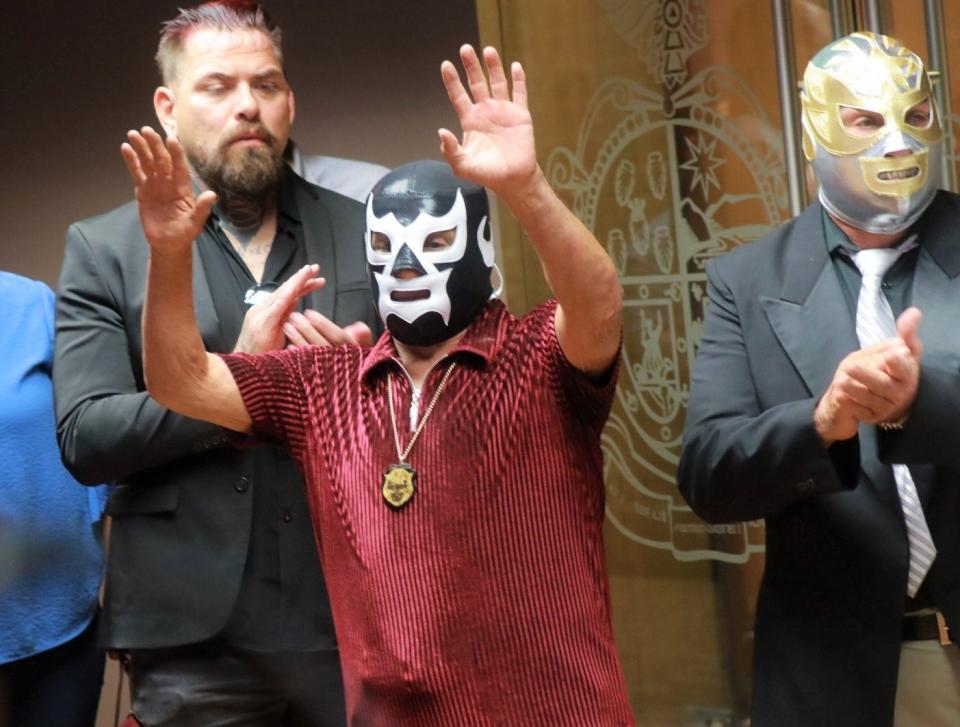 Mexican wrestler La Bestia, Fernando Urrutia Solís, (center) who began his career in 1963, is among the inductees into the Juárez Lucha Libre Hall of Fame. He waves at a news conference at Juárez City Hall.