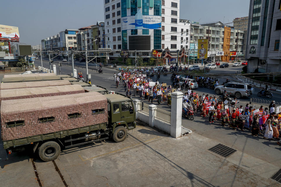 Demonstrators against the recent military coup march past a row of military vehicles in Mandalay, Myanmar, Friday, Feb. 12, 2021. Myanmar's coup leader used the country's Union Day holiday on Friday to call on people to work with the military if they want democracy, a request likely to be met with derision by protesters who are pushing for the release from detention of their country's elected leaders. (AP Photo)