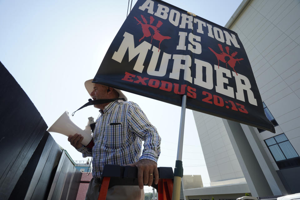 Anti-abortion activist Doug Lane holds a bullhorn with a poster behind him saying: Abortion Is Murder, Exodus 20:13.