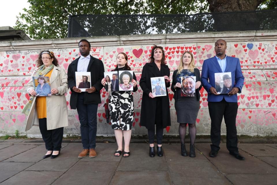 Bereaved people hold photos of loved ones lost to coronavirus (James Manning/PA) (PA Wire)