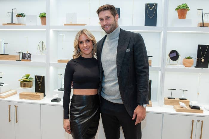 The former couple smiling for a photo at an event with various displays of jewelry behind them