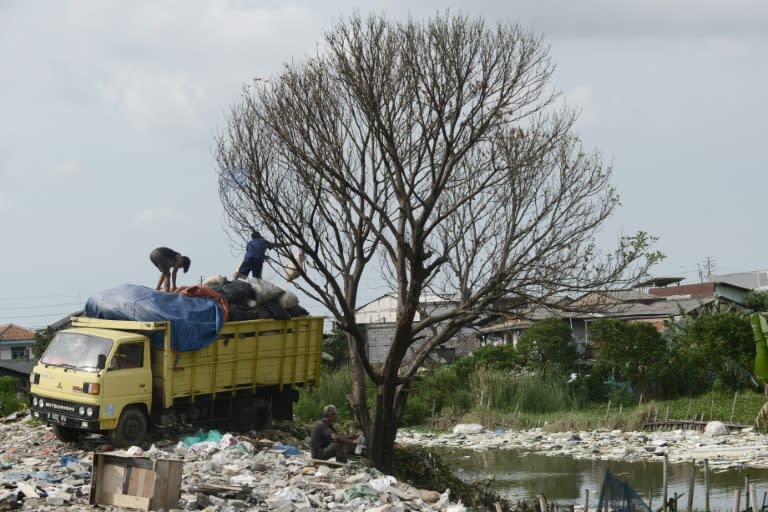 Workers unloads bags of garbage from a truck at a dumpsite in Jakarta