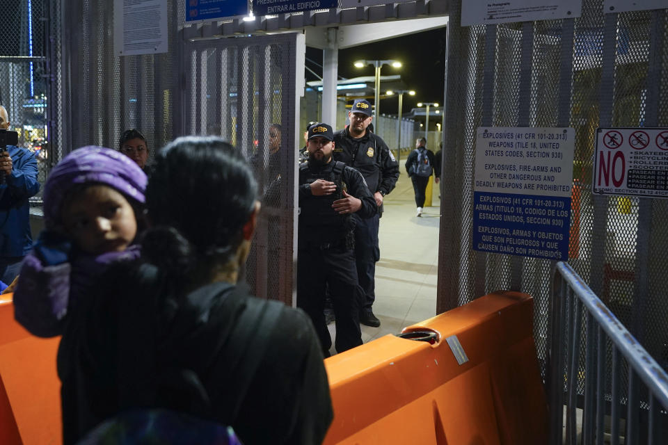 Paula, en primer plano, de Guatemala, sostiene a su hija mientras les pregunta a agentes de la Oficina de Aduanas y Protección Fronteriza de Estados Unidos acerca de las nuevas normas para el asilo, en el Puerto de Entrada de San Ysidro, el jueves 11 de mayo de 2023, en Tijuana, México. Las restricciones estadounidenses al asilo implementadas por la pandemia de COVID-19, y por las que se expulsó a migrantes millones de veces, fueron canceladas el viernes, ante lo cual mucha gente se apresuró a intentar ingresar a Estados Unidos antes de que entraran en vigor las nuevas normas anunciadas por el gobierno del presidente Joe Biden. (AP Foto/Gregory Bull)